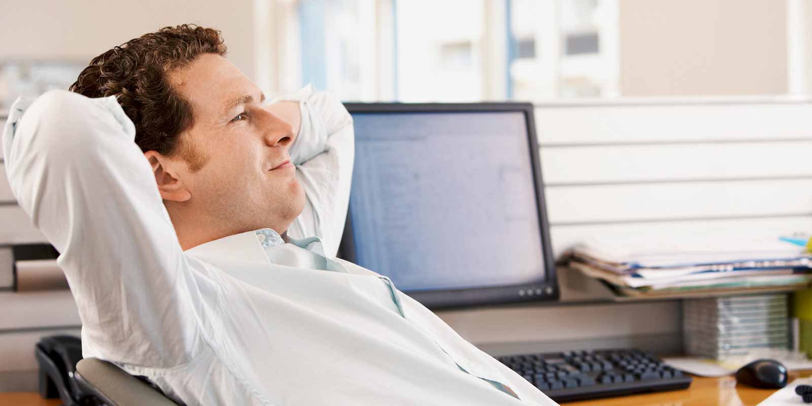 Ein Mann lehnt sich auf seinem Schreibtischstuhl zurück.
