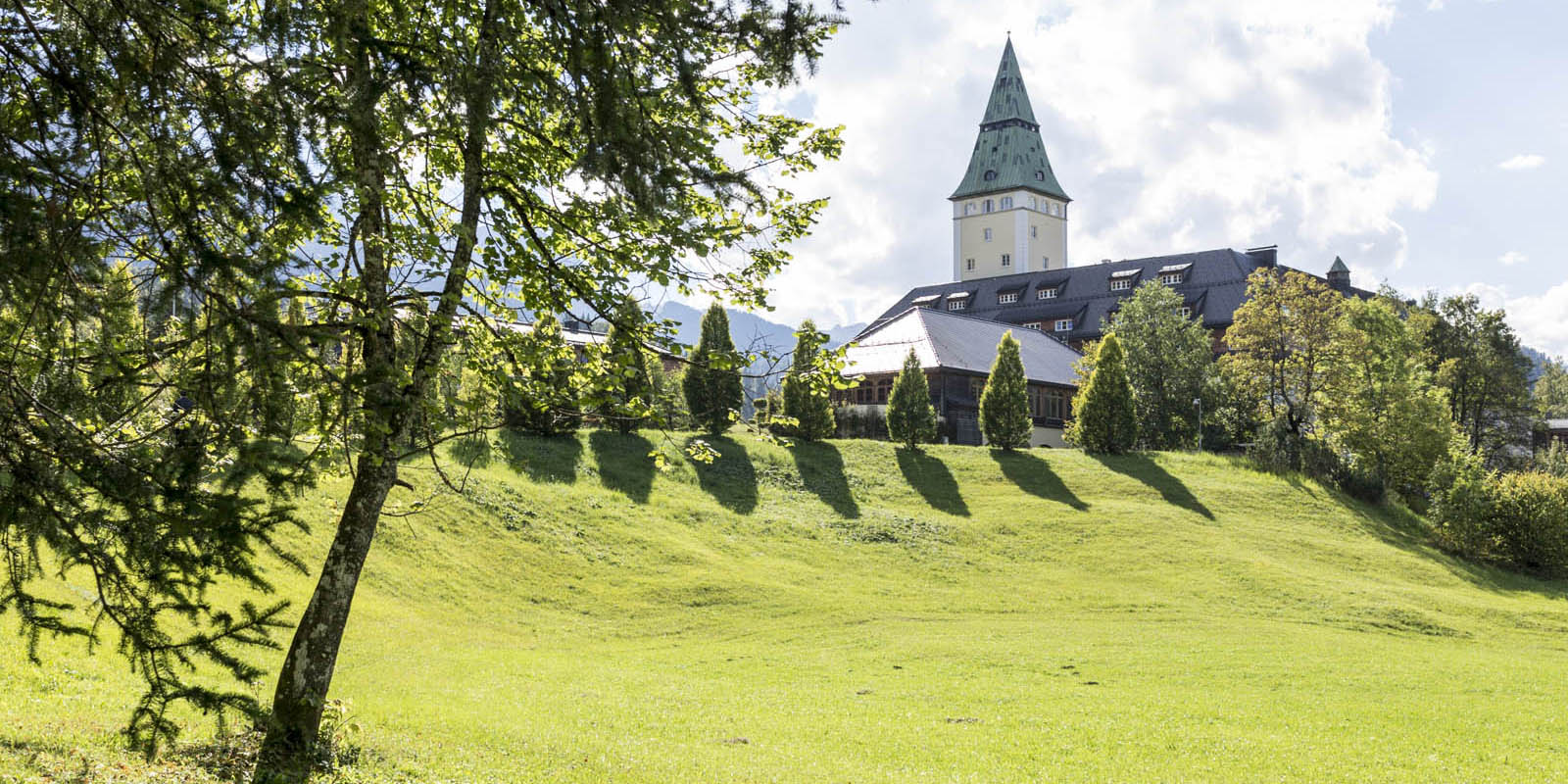 Schloss Elmau, umgeben von Wiesen und Bäumen.